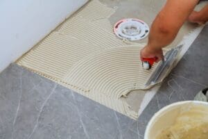 troweling a mortar on a concrete floor in preparation of tile installation