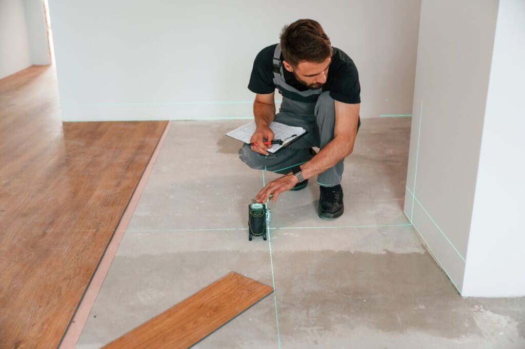 contractor using laser equipment to measure tiles to cut